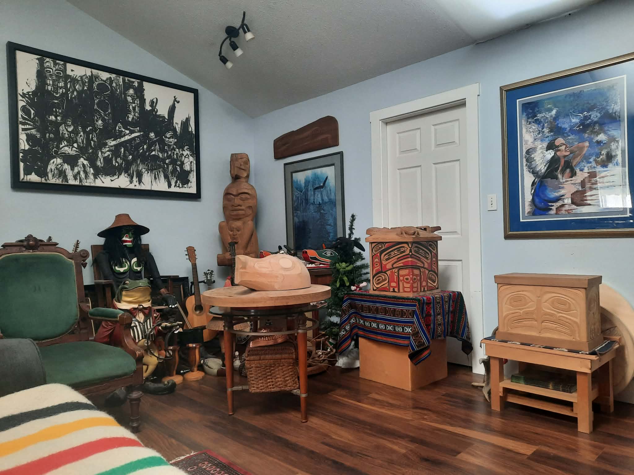 A quiet corner of the studio: carved bear, framed prints, painted bentwood box, and a green velvet chair.