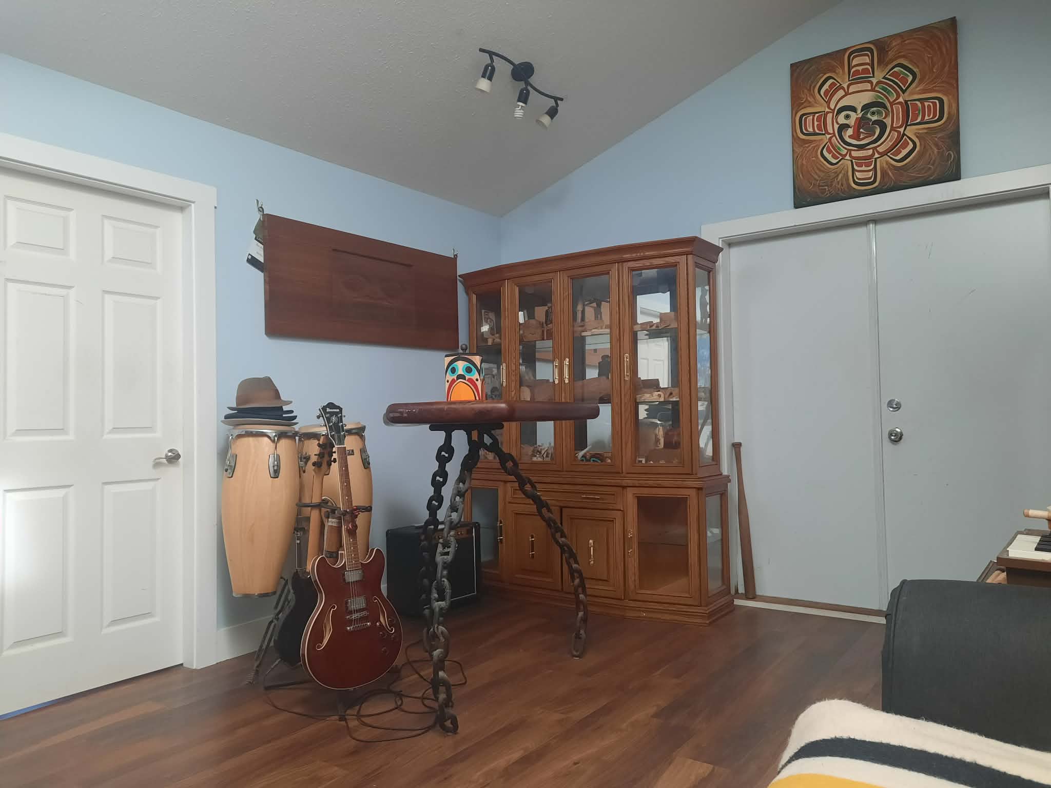 Hand-painted sun mask in traditional red and black formline, hung above a wooden door.